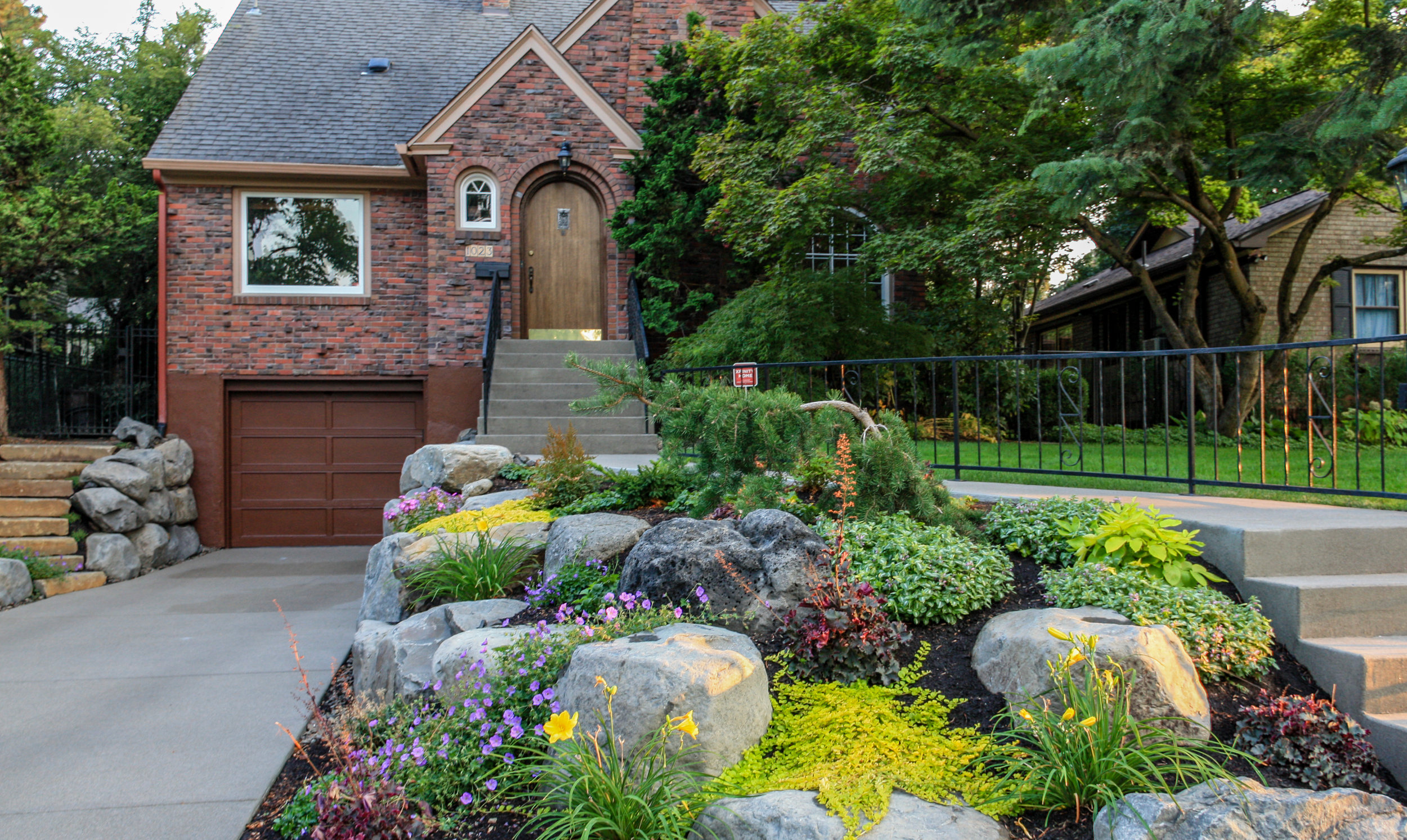 tudor brick bungalow with boulder retaining wall with rock garden