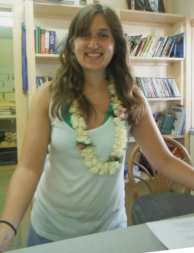 Jules working at the hostel reception in Hawaii wearing a Lei given to her by one of the guests.