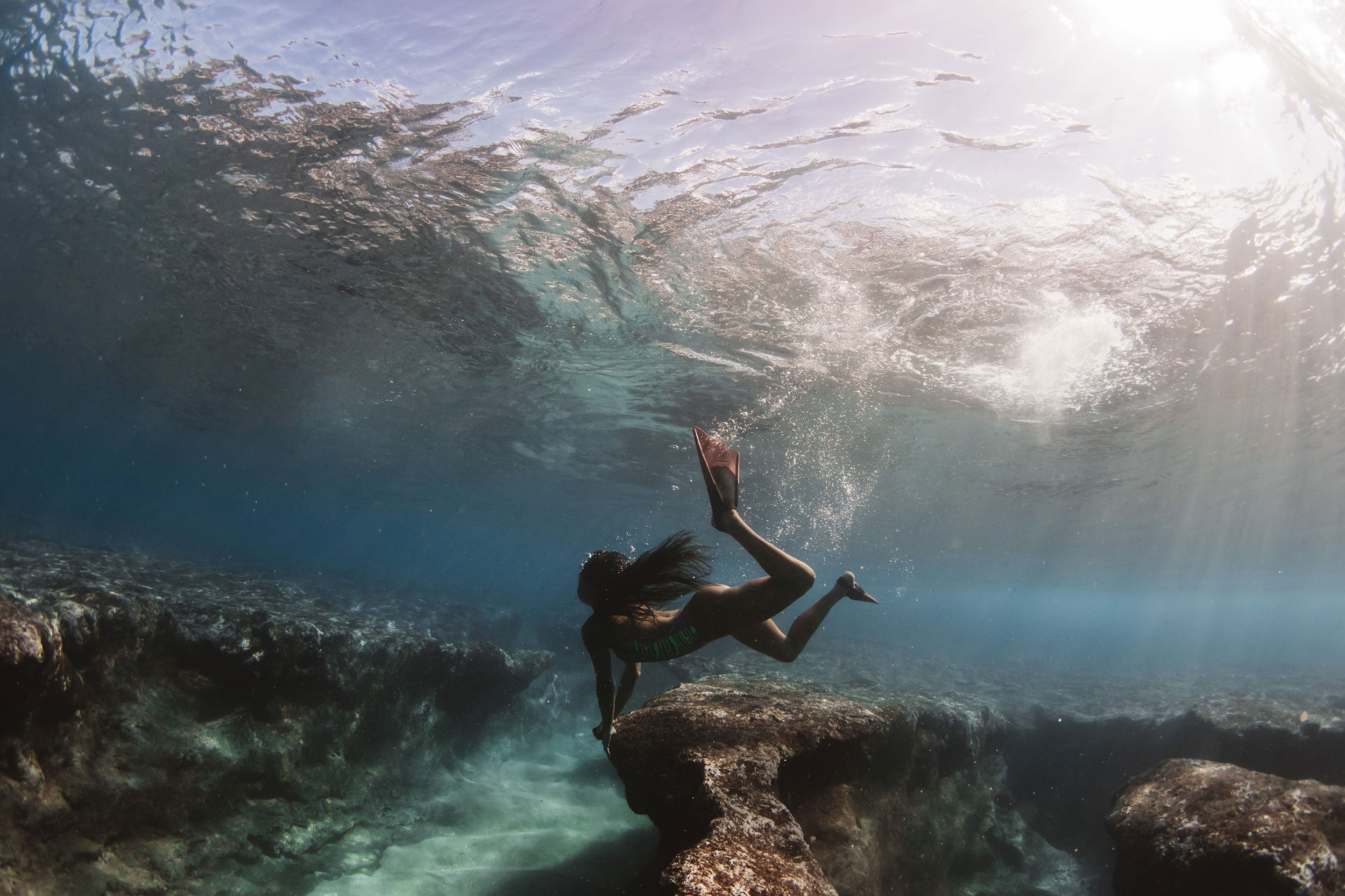 model holding onto reef at pipeline - ocean culture 