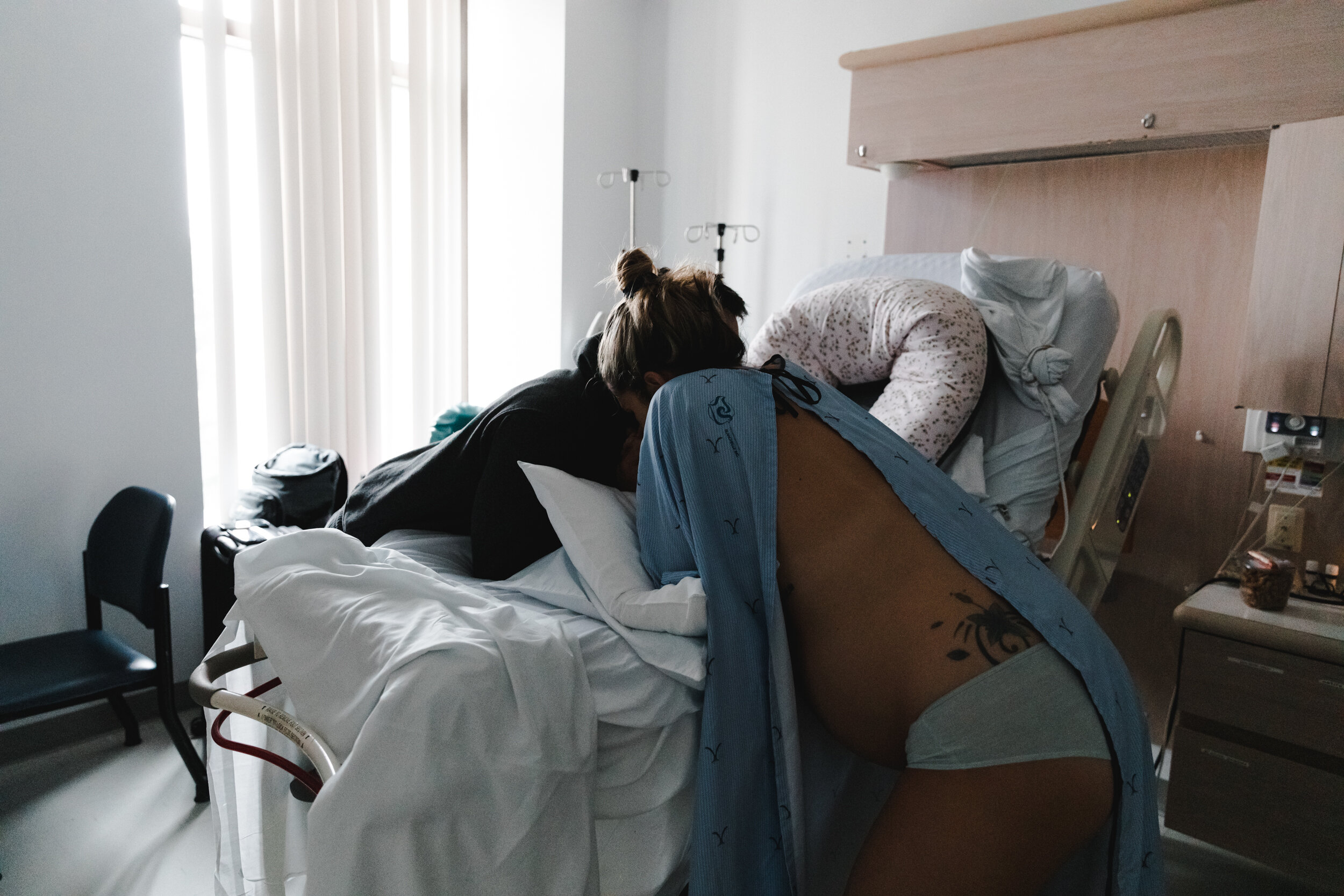 Photo de femme enceinte en jaquette d'hôpital devant lit