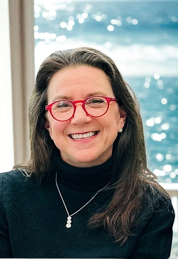 smiling woman with dark hair and red glasses