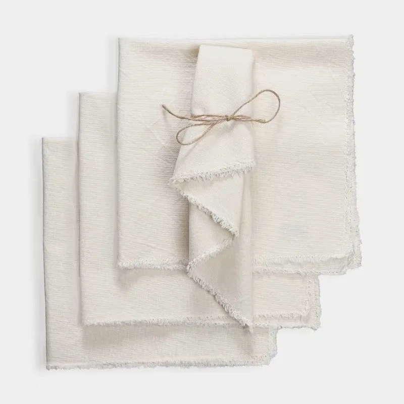 Light beige cotton linen napkin set of four with soft fringe edges, reusable cloth dinner napkins for everyday dining, weddings, and elegant table settings.