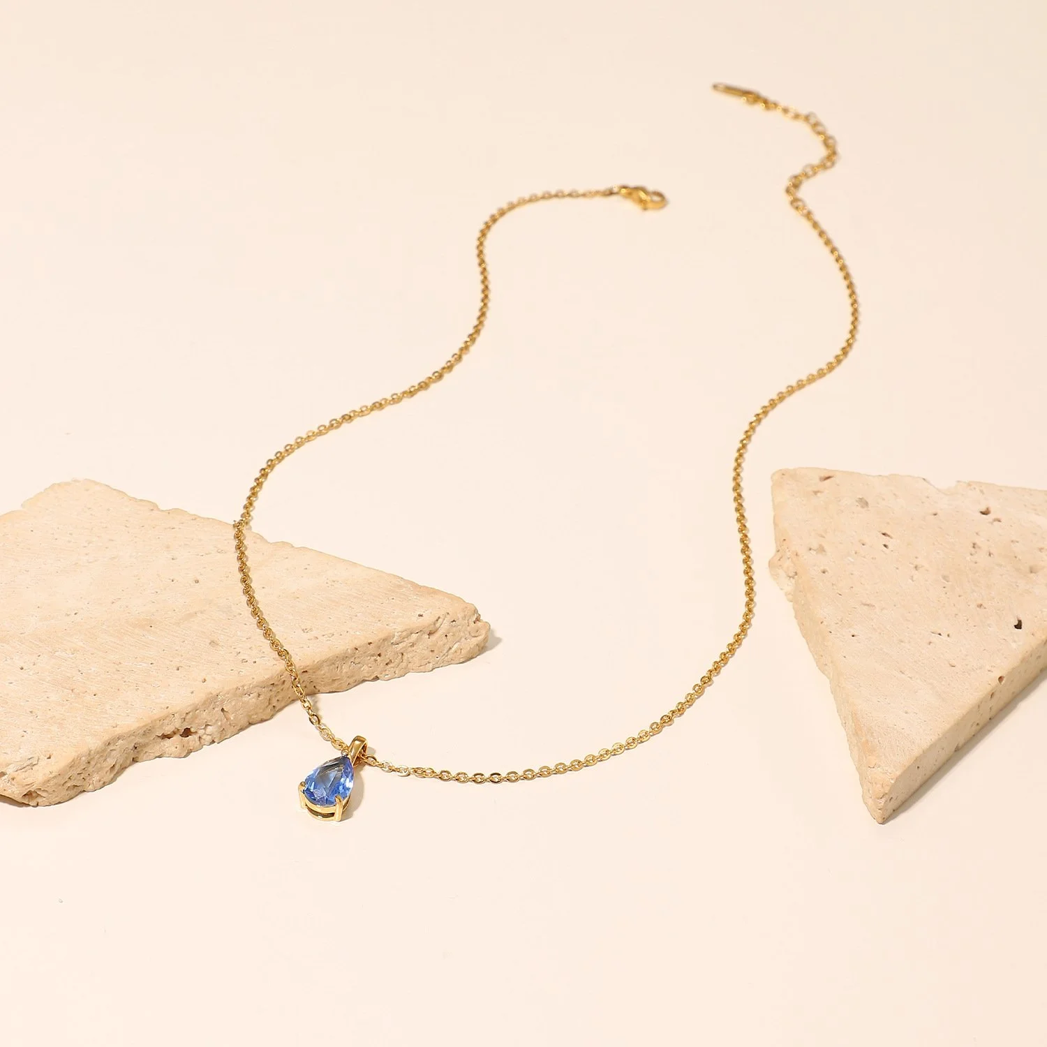 Gold chain necklace with light blue teardrop pendant gemstone for everyday wear.