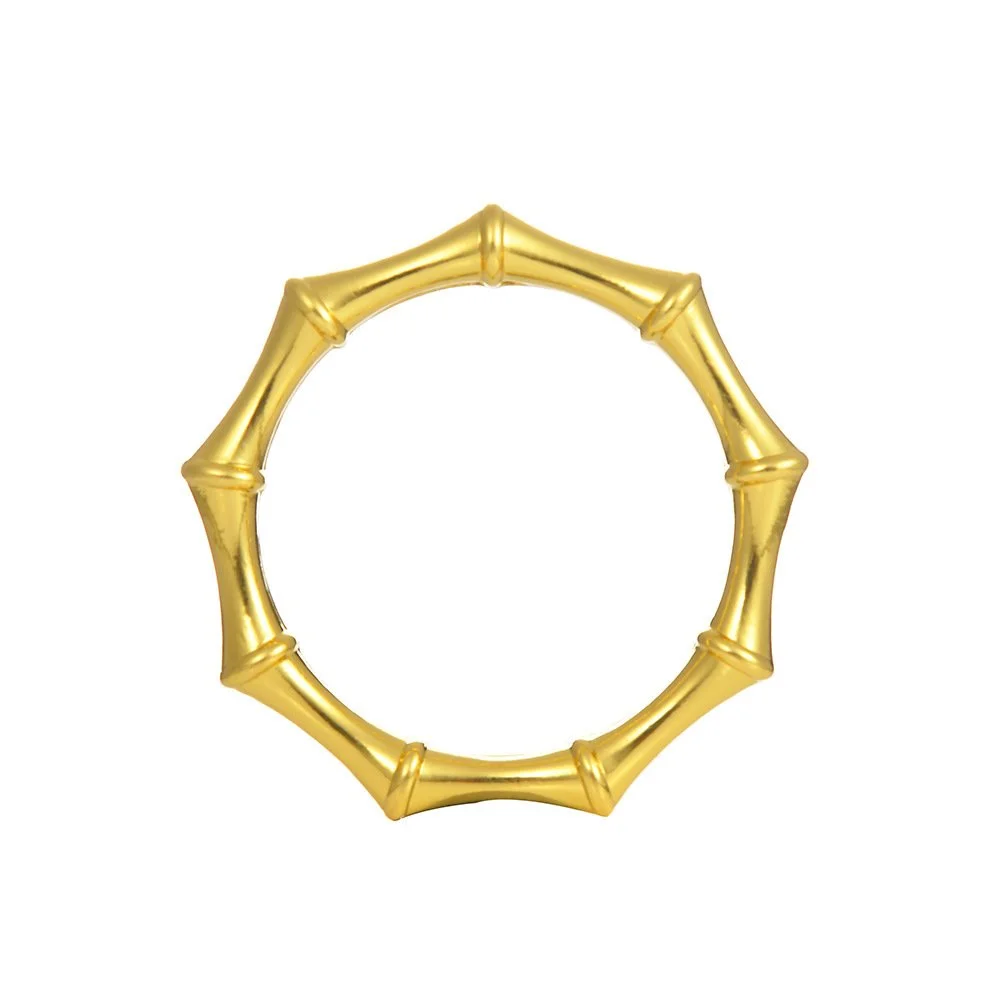 Set of four polished gold napkin rings with bamboo-inspired detailing styled on a dining table.