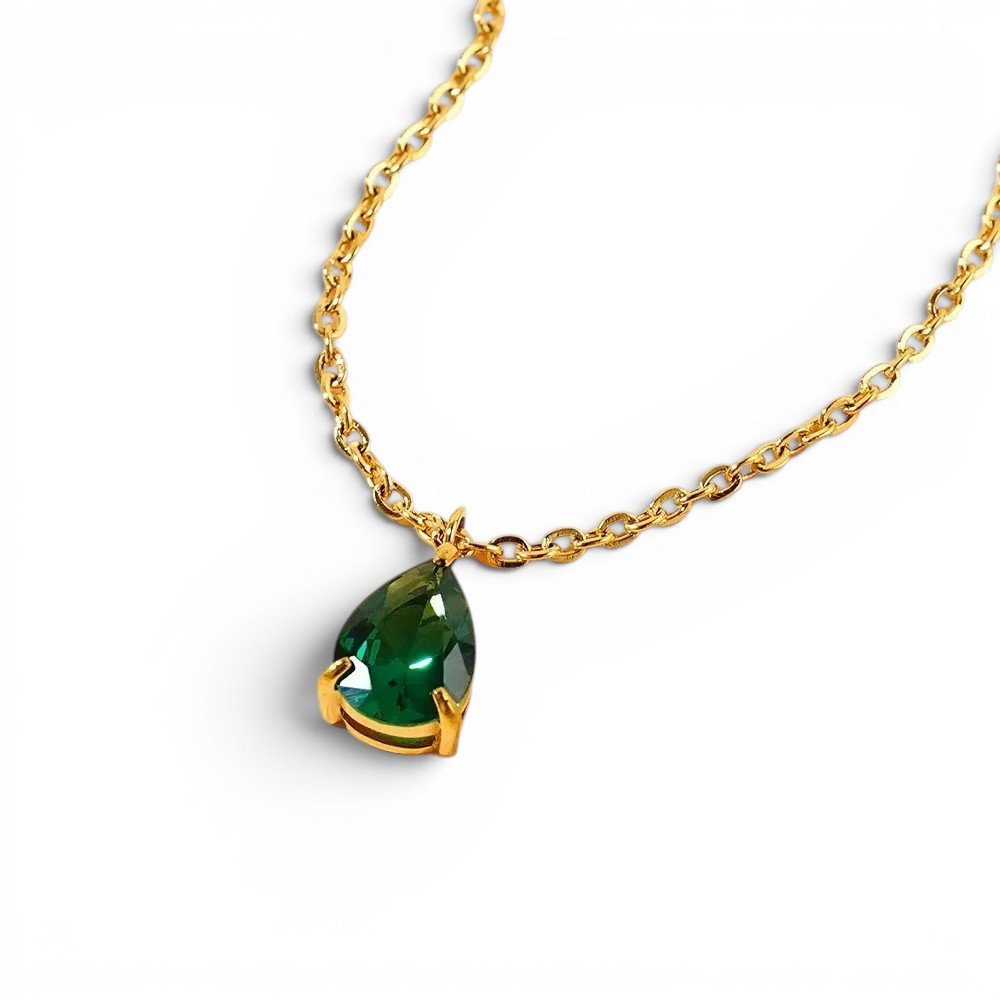 A gold chain with a teardrop shaped emerald green gemstone pendant.