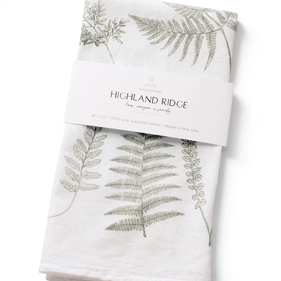 An 18" inch x 22" inch premium cotton tea towel with a light green fern pattern on a white background.