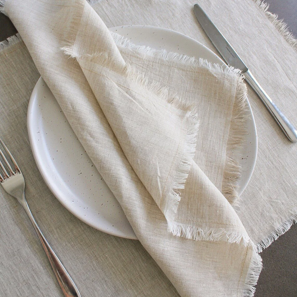 Light beige dinner napkin set displayed on table.