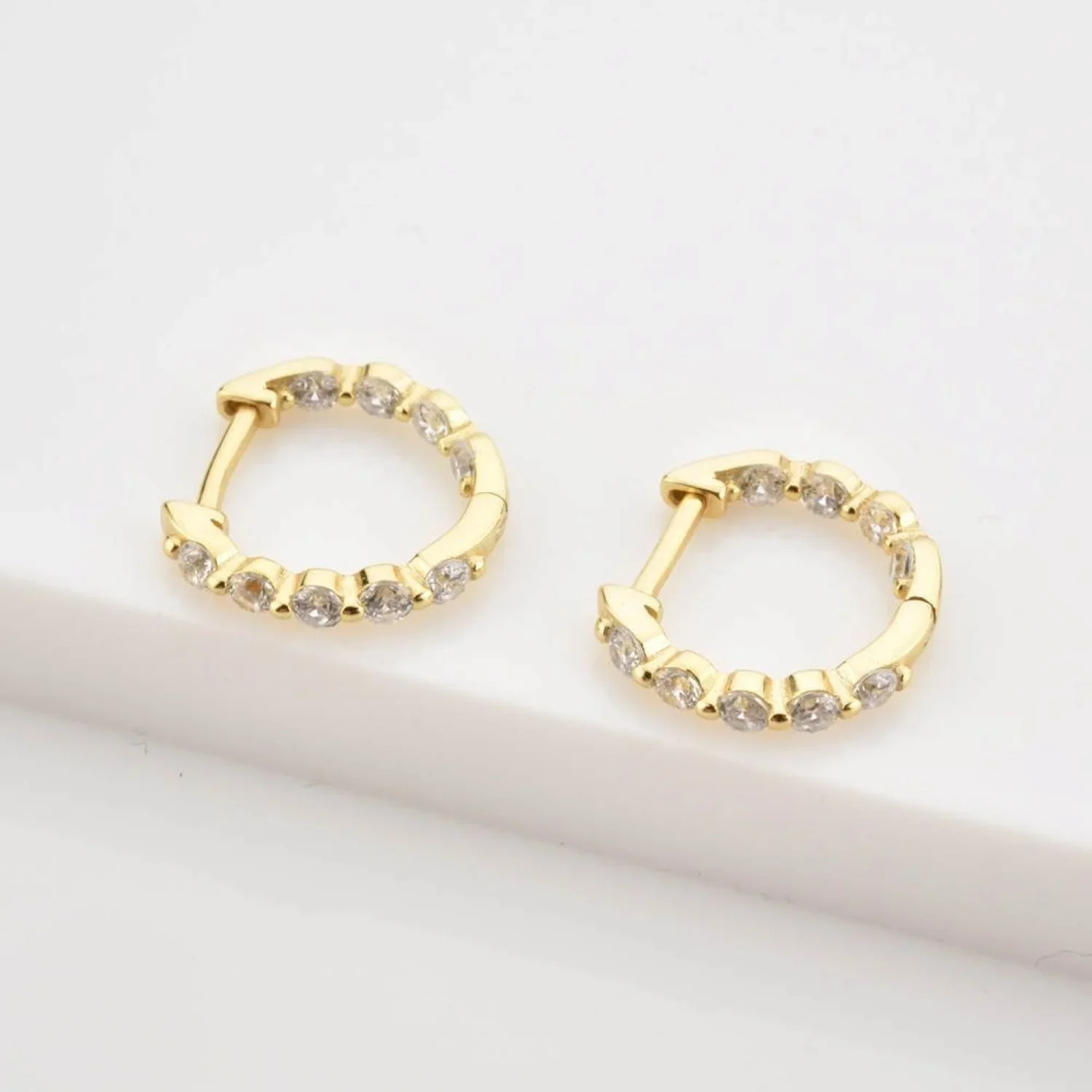 Close-up of Gold Pavé Huggie Hoop Earrings highlighting the shimmering pavé CZ details, polished gold finish, and compact huggie style.