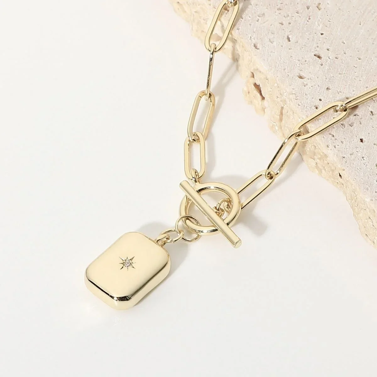 Close-up of Gold Sunburst Toggle Chain Necklace highlighting the detailed sunburst charm, textured gold finish, and elegant toggle closure.