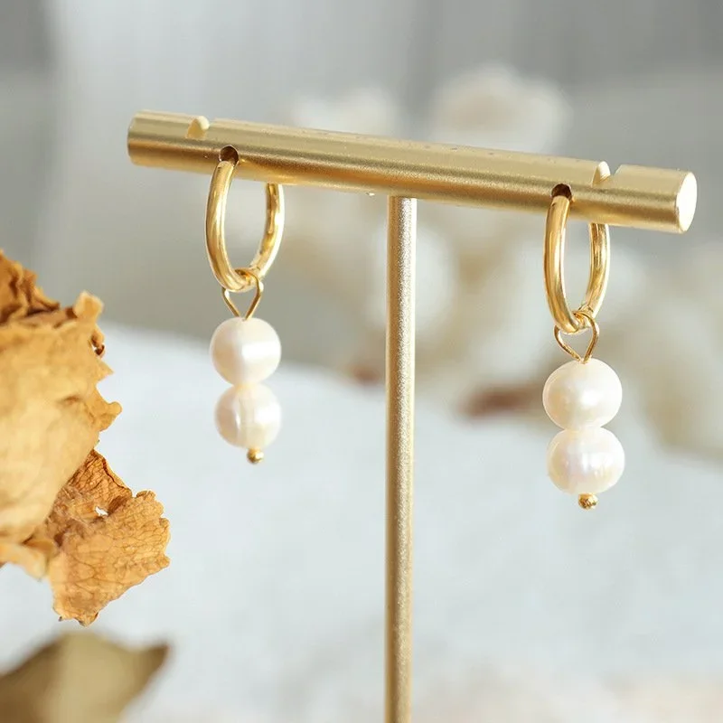 Freshwater pearl drop earrings hanging from gold polished hoops, two inches in length.