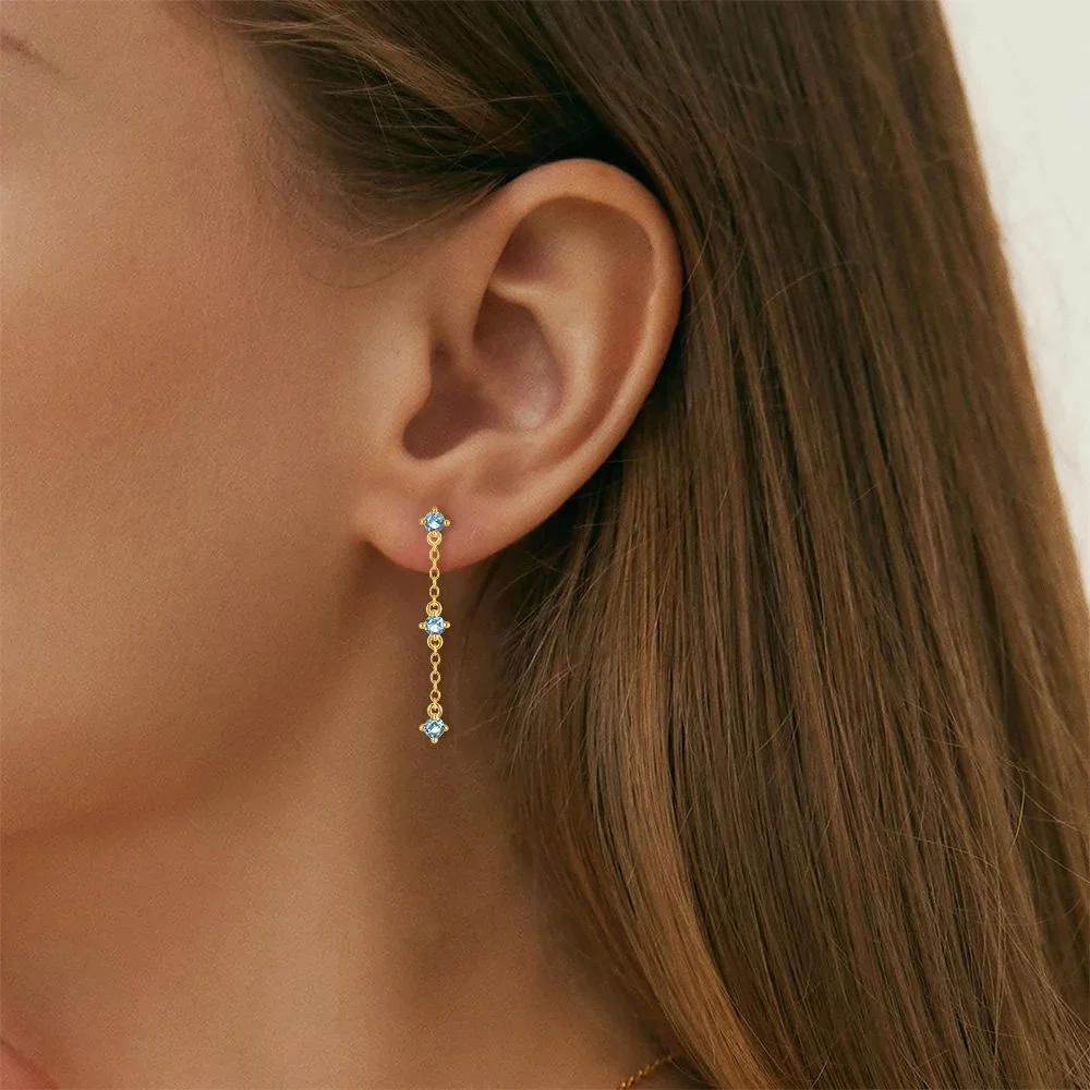 Close-up of Aria Blue CZ Gold Drop Earrings highlighting the vibrant blue CZ gemstone details, gold finish, and delicate drop silhouette.