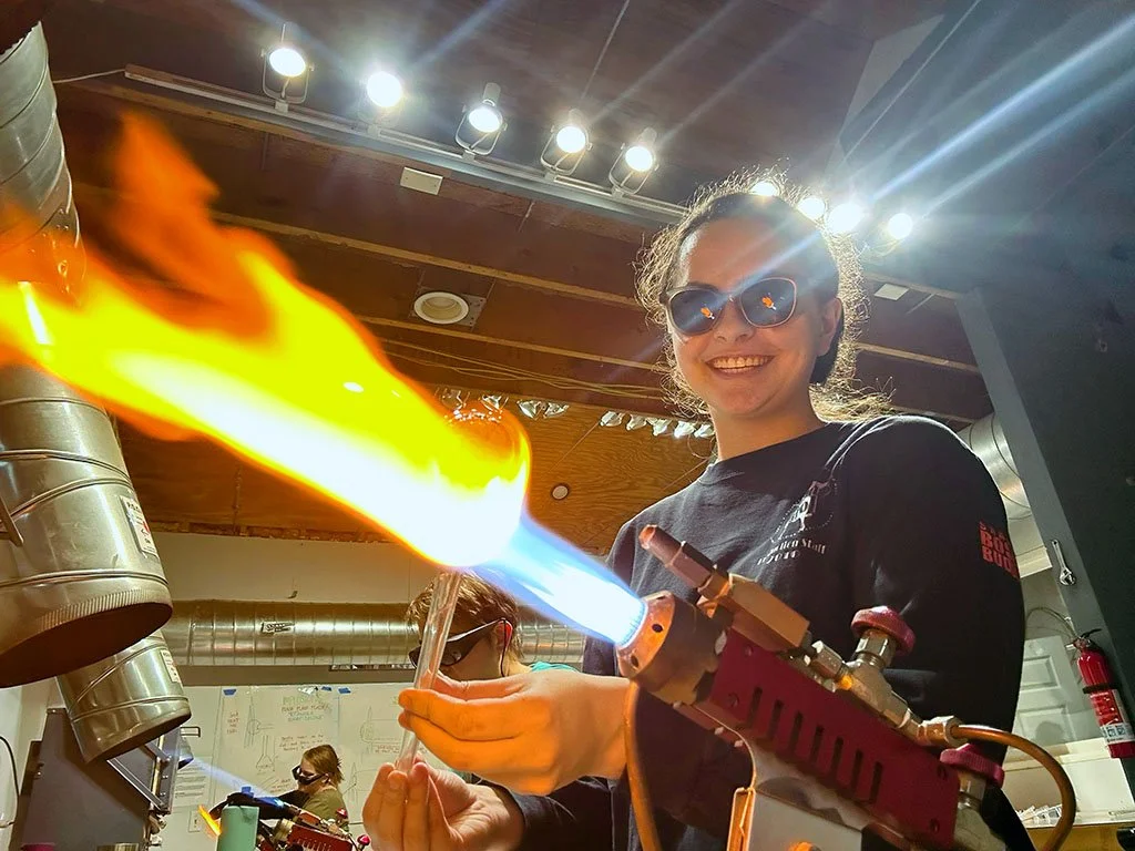 woman blowing glass in glassblowing class in flameworking studio pittsboro north carolina