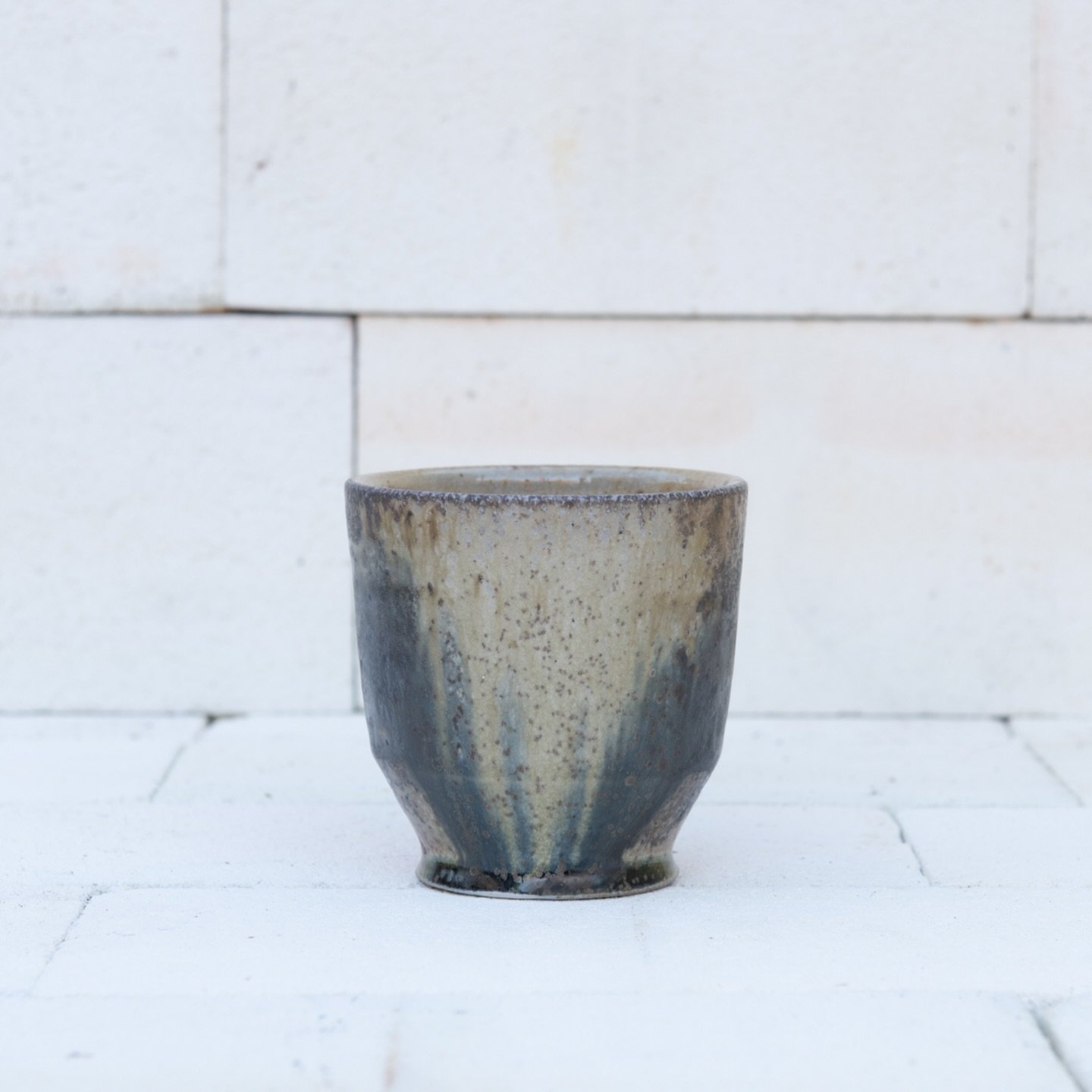 Here is a cup from the front stack of the kiln. It has some landscape like marks in black slip all the way around. In the first image, this side was facing the firebox in the kiln, accumulating enough ash to melt and cover the drawing. Swipe to revea