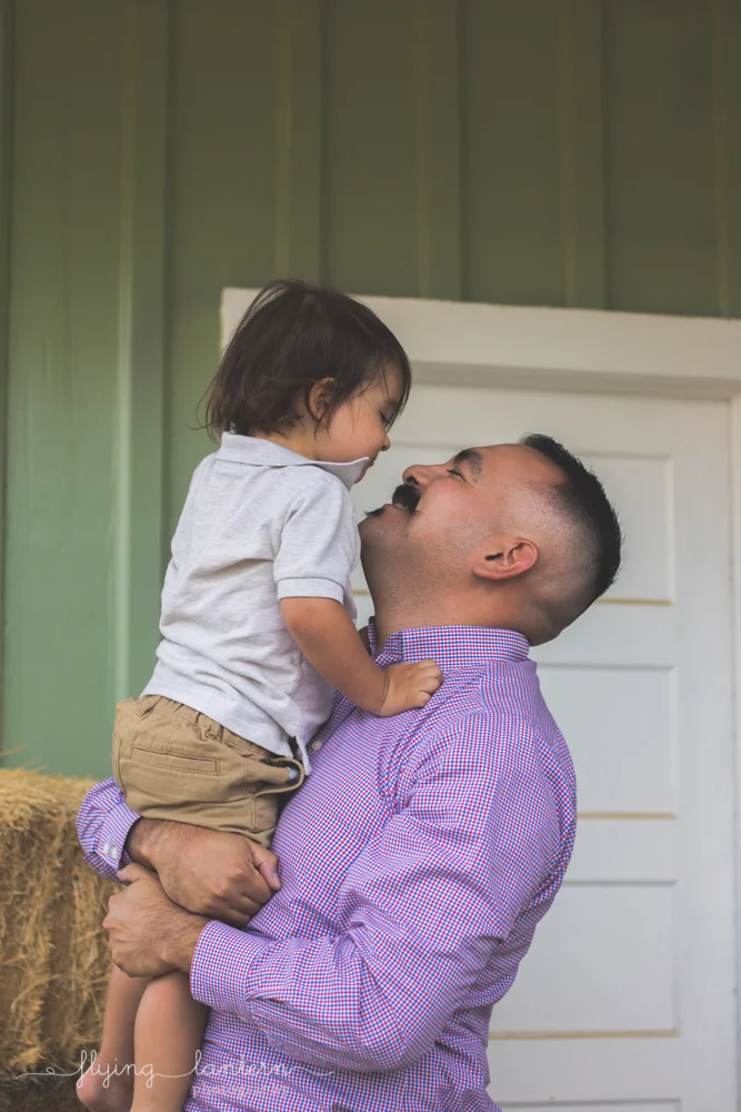 dad holding son looking up and smiling