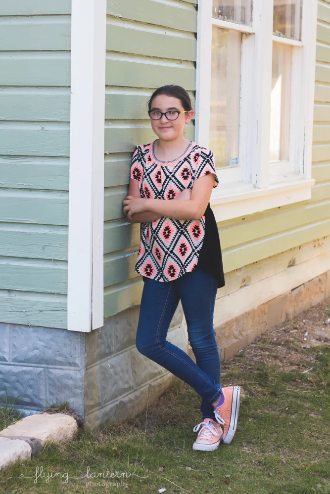 twelve year old girl leaning against side of house