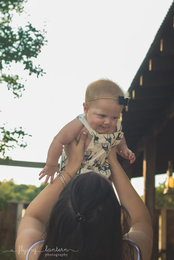 mother holding baby girl up over head