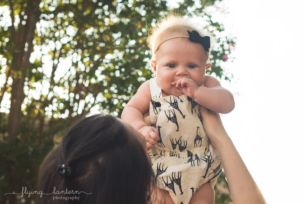 little baby being held up looking down