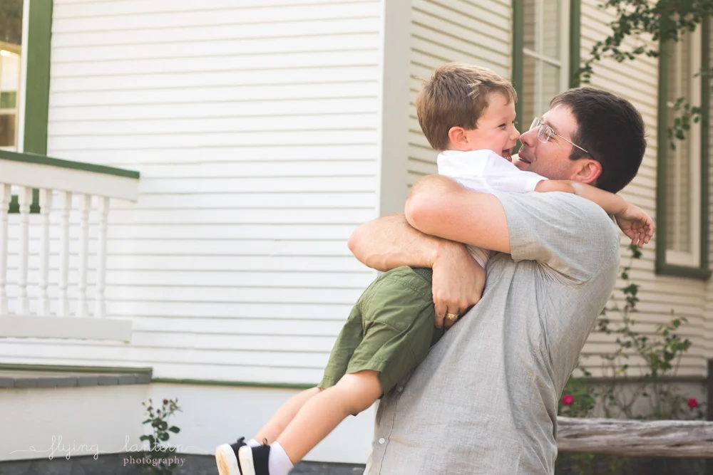 father holding onto son with bear hug