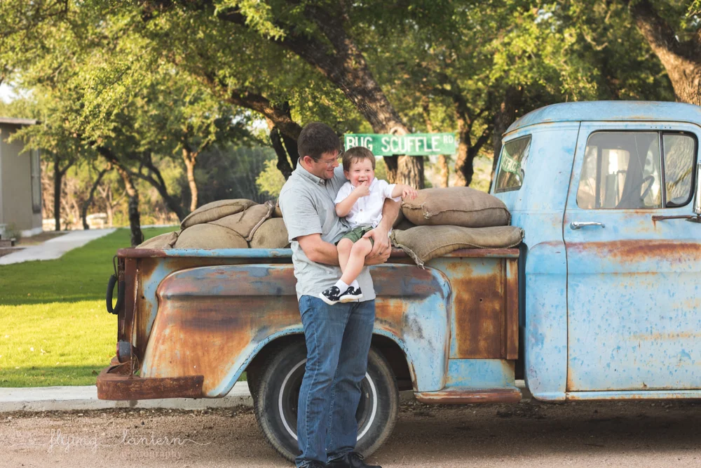 father and son standing in front of blue vintage truck
