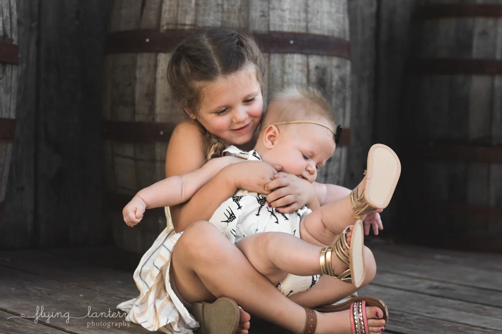 older sister holding onto baby sister in lap