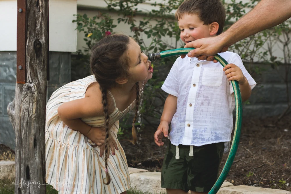 father gives water to daughter through hose