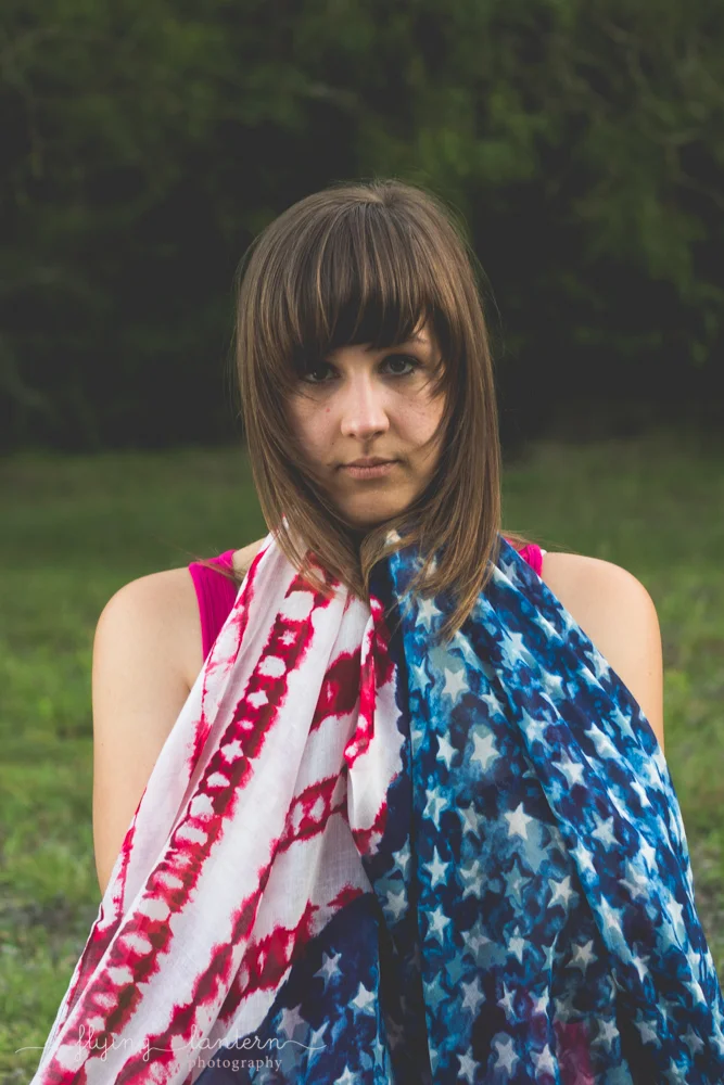 girl giving serious look at camera with flag up to chin draping down