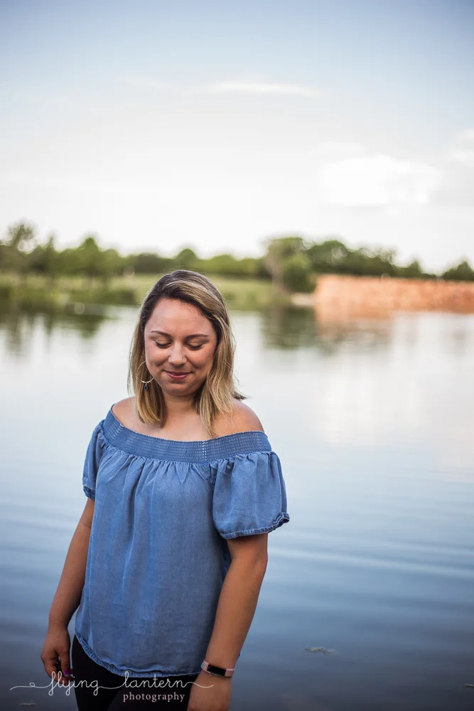Austin food blogger lifestyle portrait session at Mueller Lake Park. Half body photo. Woman wearing chambray off the shoulder blouse and black jeans. Photo by Erin Reas of Flying Lantern Photography