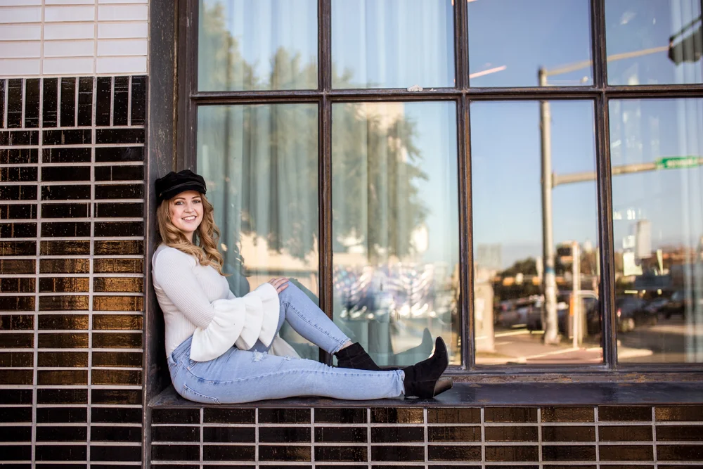 Girl senior portrait outside South Congress Hotel wearing white sweater with bell sleeves. Photo by Erin Reas photographer in Austin, TX