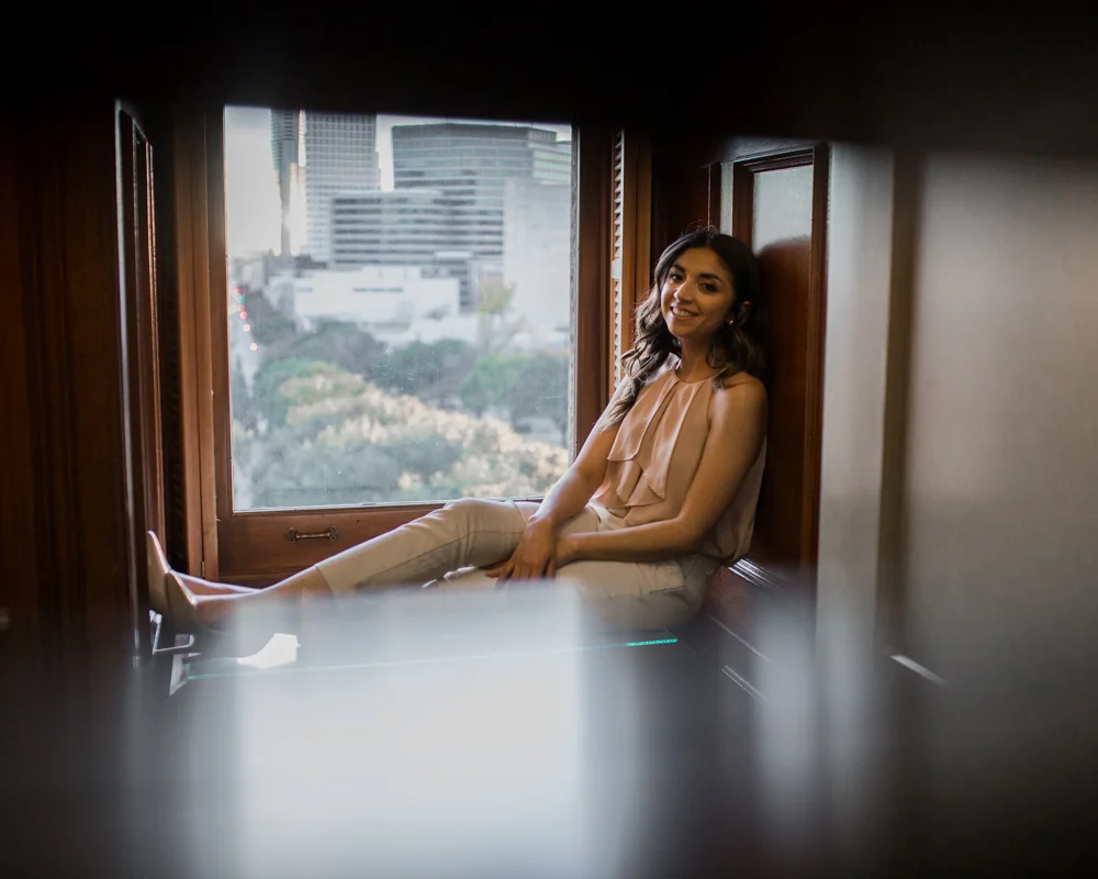 college graduate senior portrait in texas state capitol building. inside her office sitting next to window. photo by erin reas austin photographer