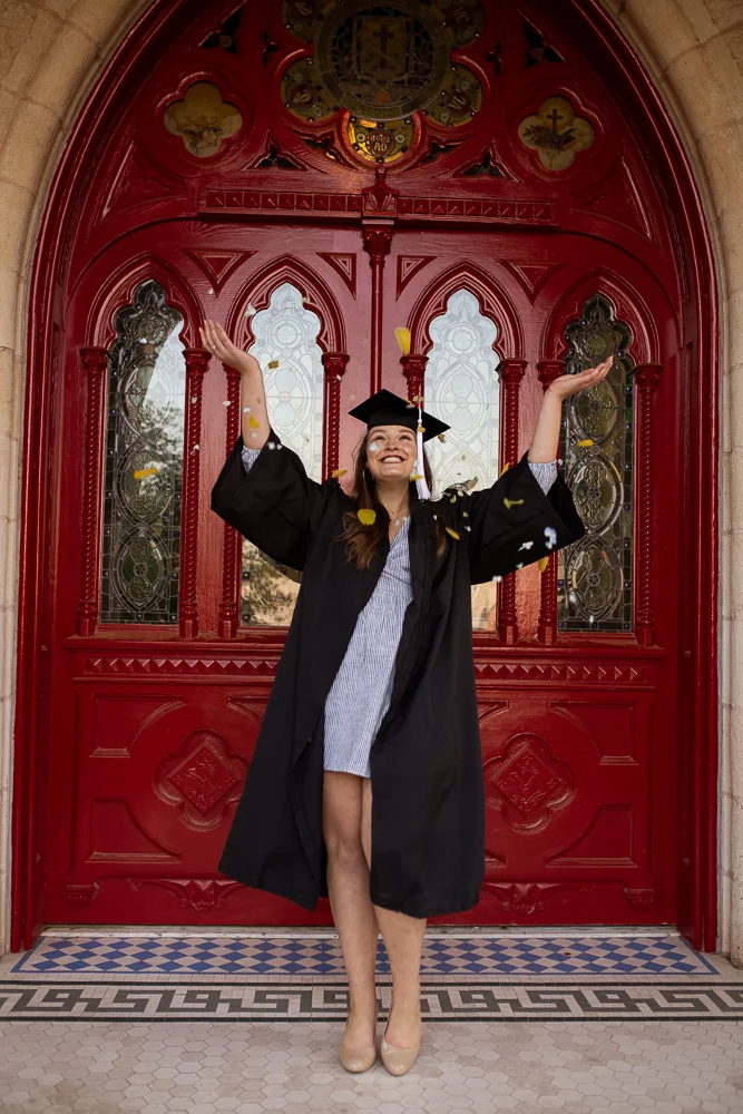 Female college graduate throwing blue and yellow flower petals. Photo by Erin Reas Austin, TX senior photographer