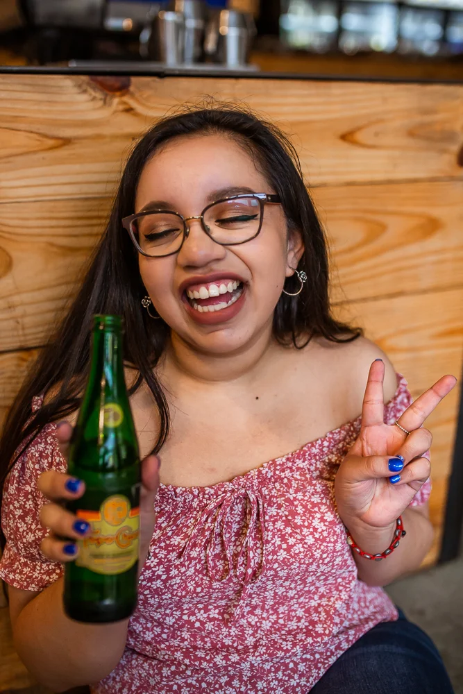 College graduate drinking Topo Chico during senior portrait session at St. Edward’s University. Photo by Erin Reas senior photographer in Austin, TX