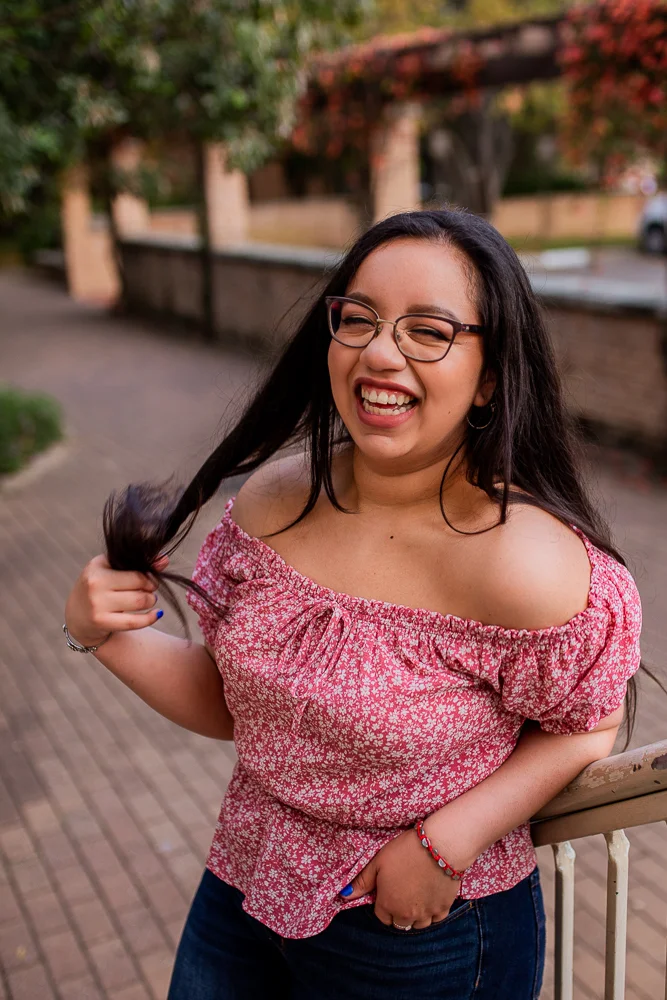 Female college graduate wearing red floral top and glasses at St. Edward’s University in Austin, TX. Photo by Erin Reas local senior photographer