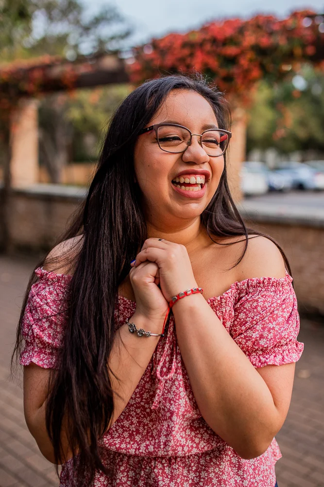Female college graduate wearing red floral top and glasses at St. Edward’s University in Austin, TX. Photo by Erin Reas local senior photographer