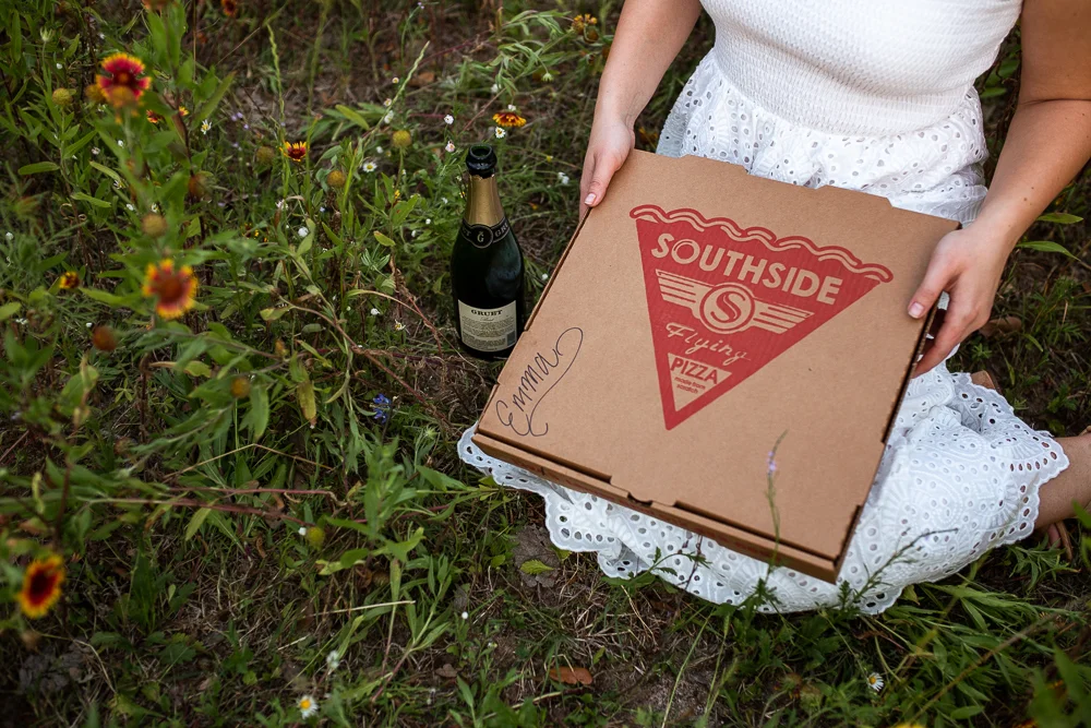 Southside Flying Pizza pizza box with bottle of champagne. Photo by Erin Reas senior photographer in Austin, TX