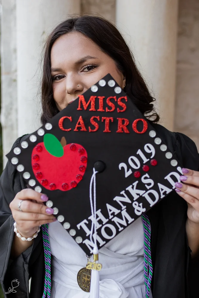 College graduate holding decorated graduation cap. Graduate with a teaching degree at St. Edward’s University. Photo by Erin Reas senior photographer in Austin, Texas