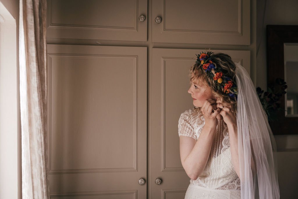 12_Bride applies earrings in The Normans Cottage. Photo by Jules Barron.jpg