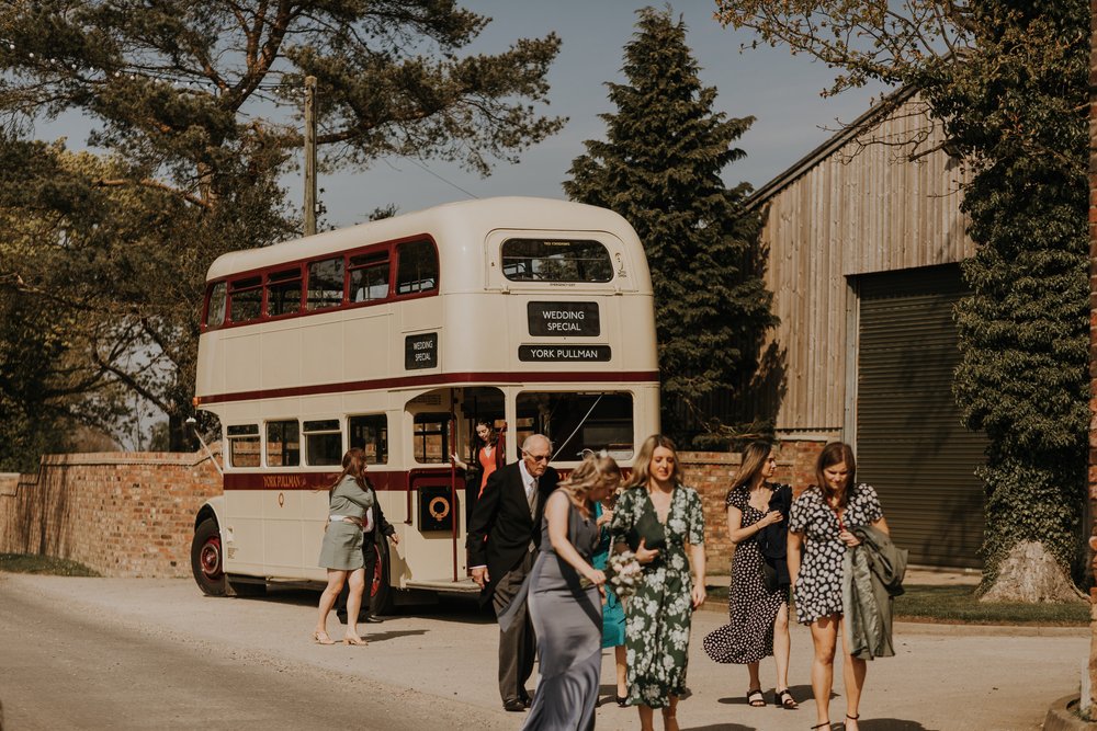 Double decker bus drops wedding guests at The Normans wedding venue. Photo by Louise Anna Photography.jpg