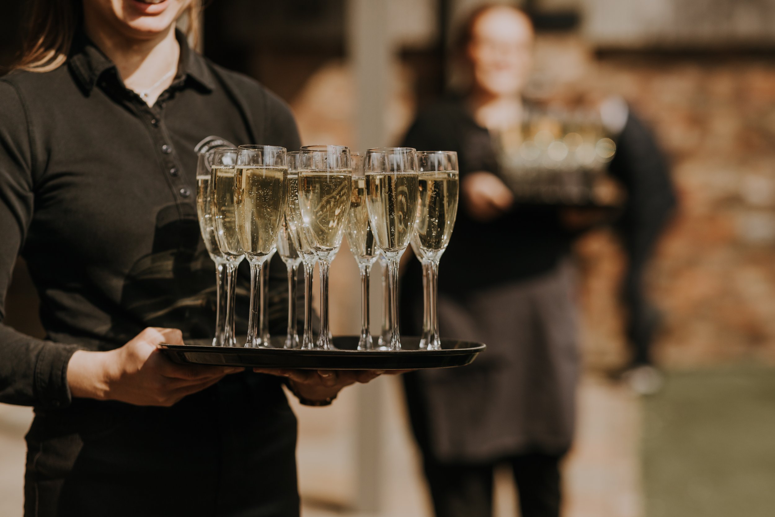 Hog & Apple await wedding guests with trays of champagne at The Normans wedding venue. Photo by Louise Anna Photography.jpg