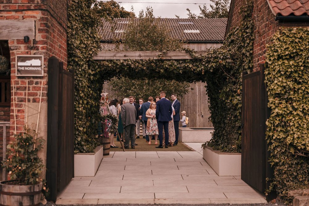 01_Guests congregate in The Normans wedding venue Courtyard. Photo by Jules Barron.jpg