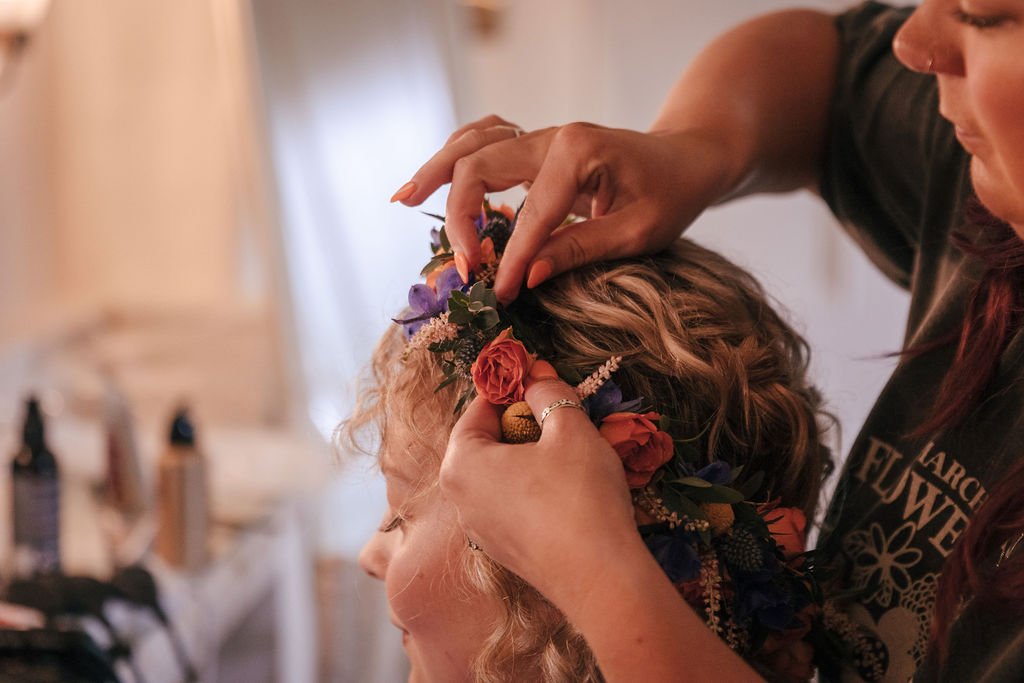 12_Bride has her floral headdress adjusted in The Normans Cottage dressing room. Photo by Jules Barron.jpg