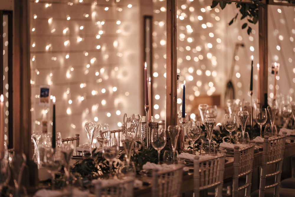 25_Sparkling lights and rustic banqueting tables in The Normans wedding venue Grain Shed. Photo by Jules Barron.jpg