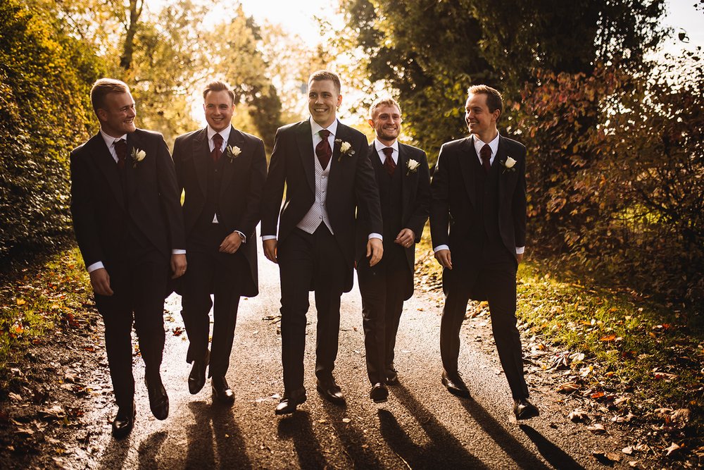 01_Groom and groomsmen walk outside The Normans wedding venue in autumn sunshine. Photo by Lumiere Photographic.jpg
