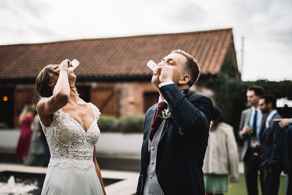 21a_Bride and groom drink mini pints in The Normans wedding venue Courtyard. Photo by Lumiere Photographic.jpg