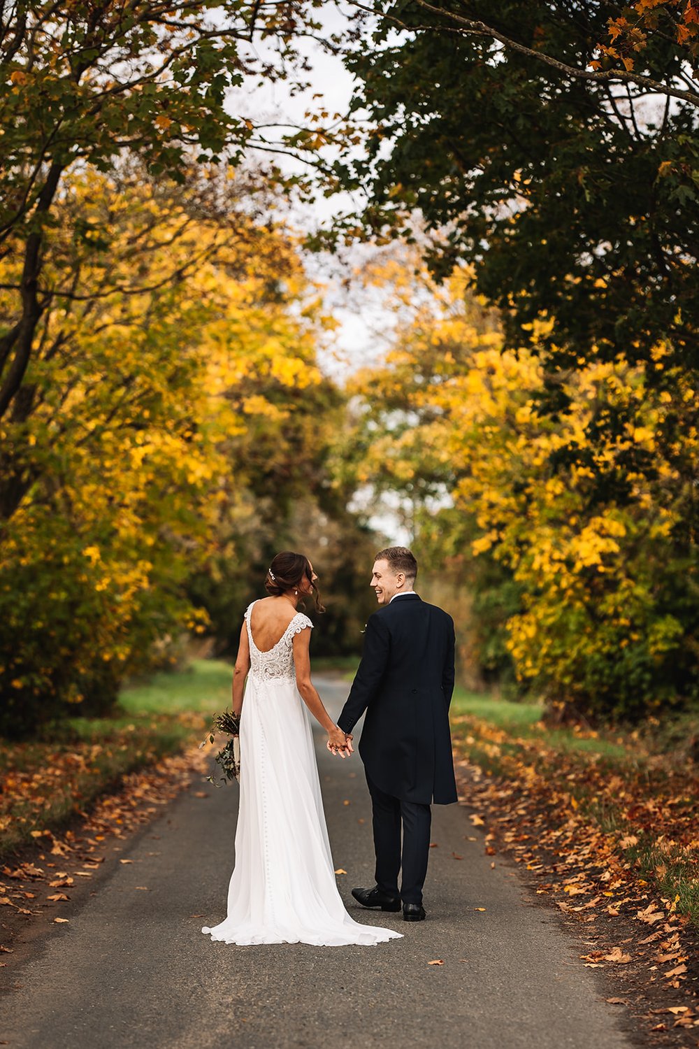 22_Bride and Groom stroll outside the venue amidst autumn leaves Photo by Lumiere Photographic.jpg
