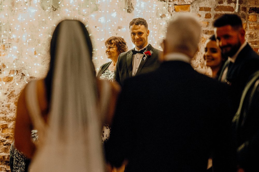 03a_Bride and her dather walk down the The Normans wedding venue Ceremony Barn aisle. Photo by Hamish Irvine.jpg