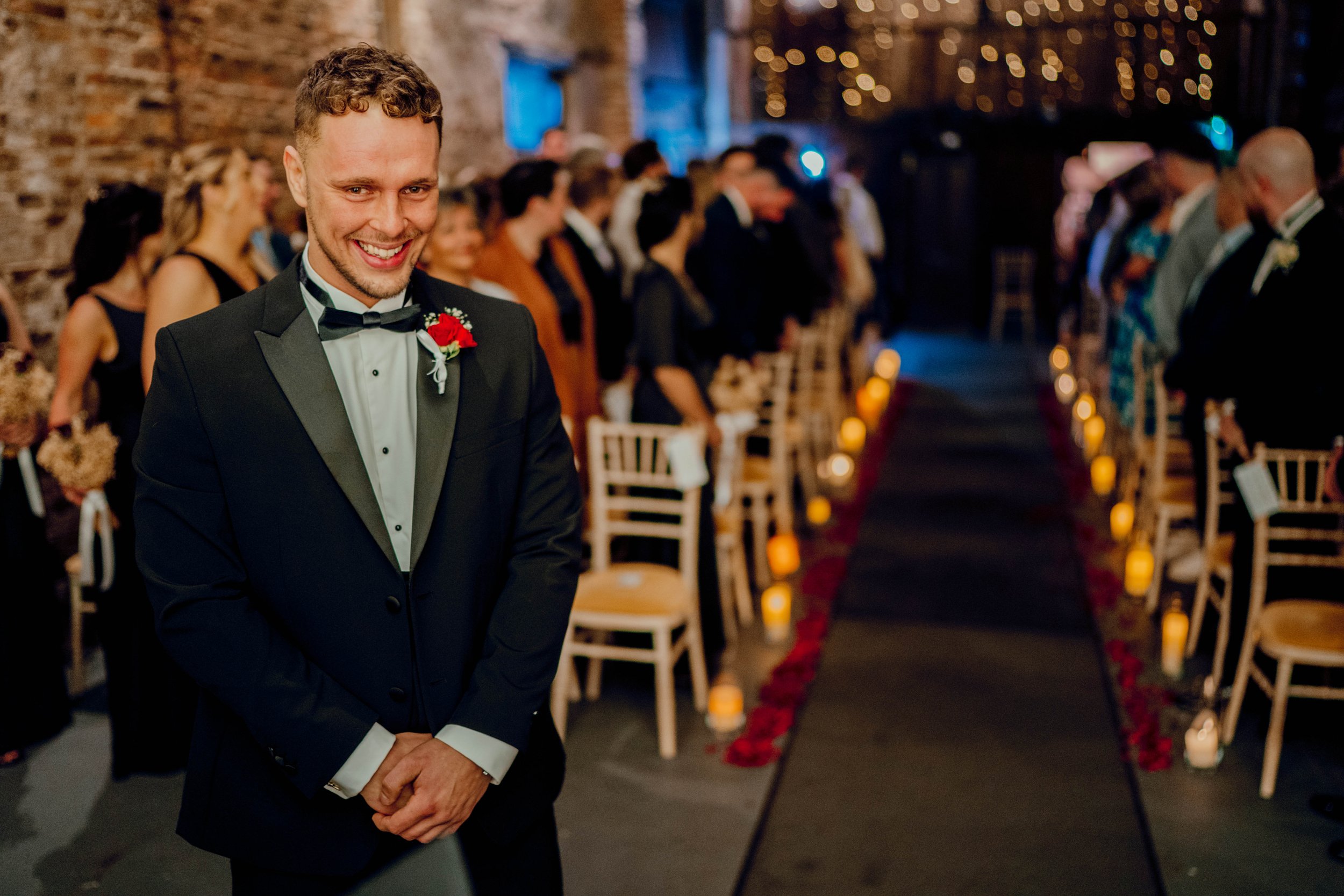 03_Groom awaits entrance of bride in The Normans wedding venue Ceremony Barn. Photo by Hamish Irvine.jpg