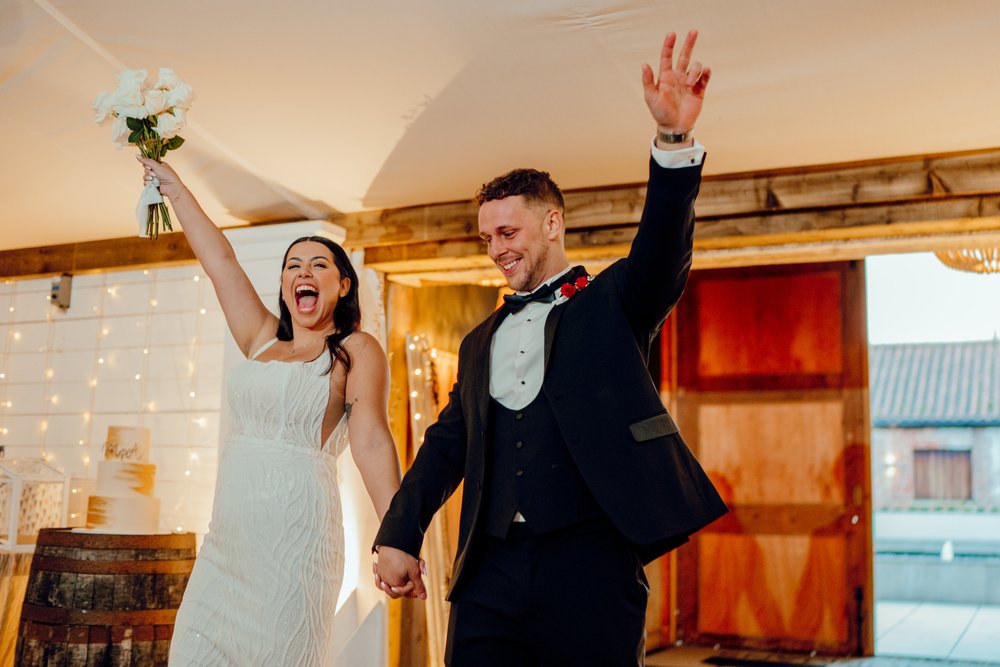 08a_Bride and groom enter The Normans wedding venue Grain Shed dining area. Photo by Hamish Irvine.jpg