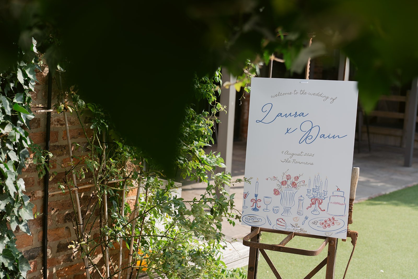 wedding-welcome-sign-through-greenery-courtyard.jpg