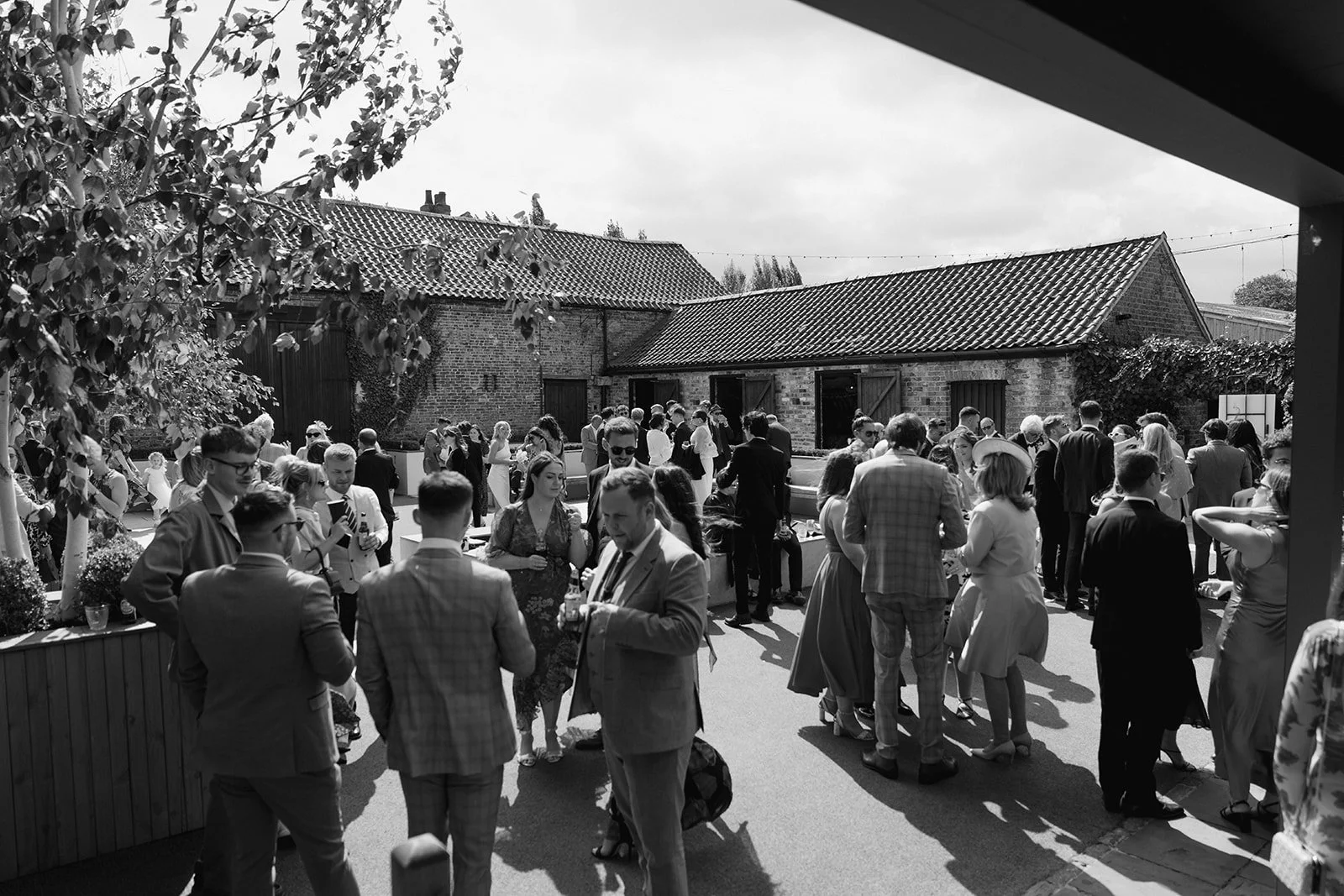 wedding-guests-mingling-courtyard-brick-barns.jpg
