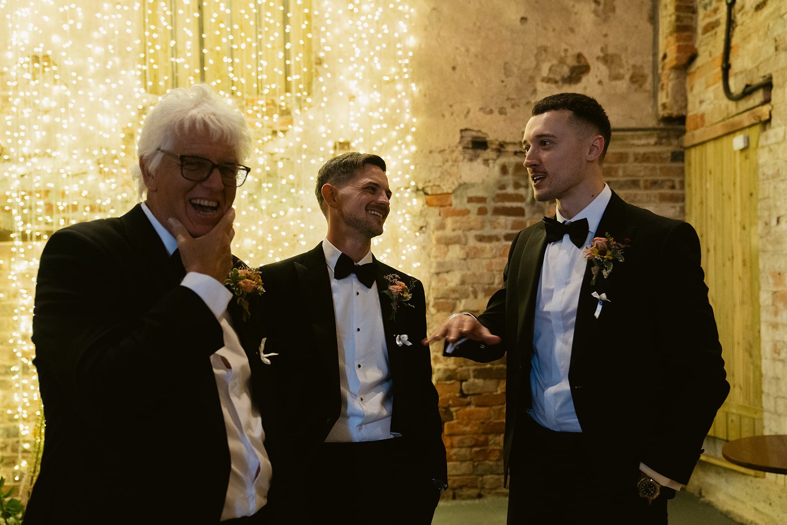 groom-laughing-groomsmen-fairy-light-wall-pre-ceremony.jpg